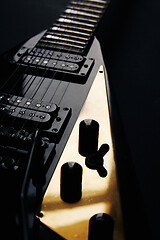 Image showing Black V shape electric guitar on dark grunge background.