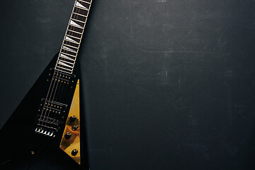 Image showing Black V shape electric guitar on dark grunge background.