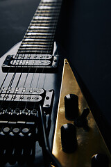 Image showing Black V shape electric guitar on dark grunge background.
