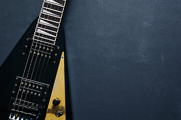 Image showing Black V shape electric guitar on dark grunge background.