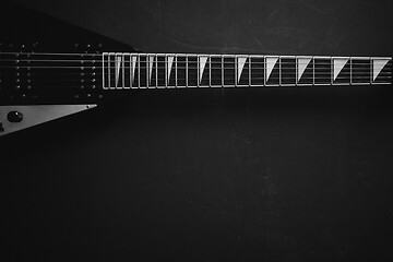 Image showing Black V shape electric guitar on dark grunge background.