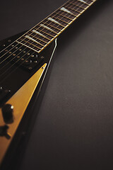 Image showing Black V shape electric guitar on dark grunge background.