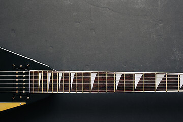 Image showing Black V shape electric guitar on dark grunge background.