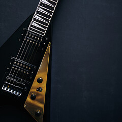 Image showing Black V shape electric guitar on dark grunge background.