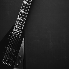 Image showing Black V shape electric guitar on dark grunge background.