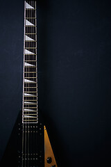 Image showing Black V shape electric guitar on dark grunge background.