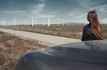 Image showing Woman leaning to her car next to the wind turbines site