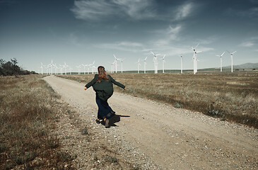 Image showing Woman with long tousled hair next to the wind turbine with the w