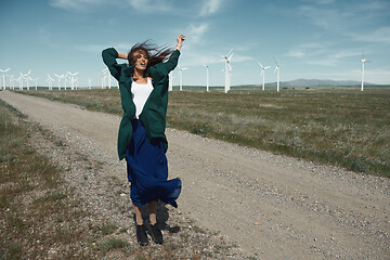 Image showing Woman with long tousled hair next to the wind turbine with the w