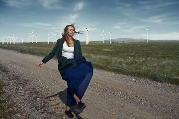 Image showing Woman with long tousled hair next to the wind turbine with the w