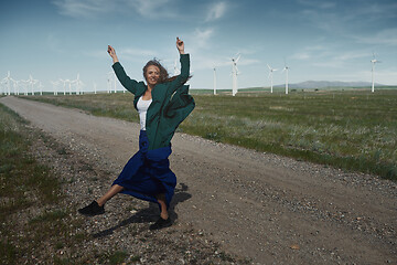 Image showing Woman with long tousled hair next to the wind turbine with the w