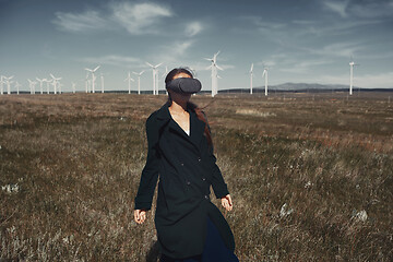 Image showing Woman wearing VR headset at the field next to the wind turbines