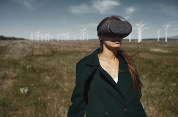 Image showing Woman wearing VR headset at the field next to the wind turbines