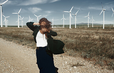 Image showing Woman with long tousled hair next to the wind turbine with the w