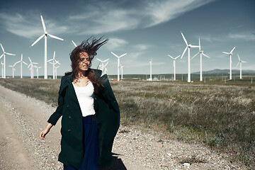 Image showing Woman with long tousled hair next to the wind turbine with the w
