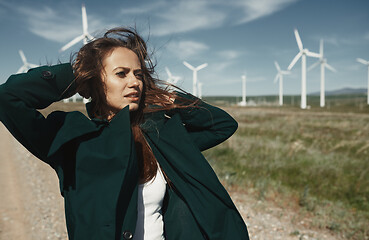 Image showing Woman with long tousled hair next to the wind turbine with the w