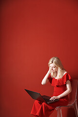 Image showing Young adult woman sitting on a chair and working on laptop