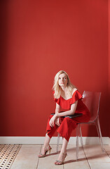 Image showing Young adult woman sitting on a chair and holding laptop