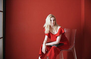 Image showing Young adult woman sitting on a chair and holding laptop