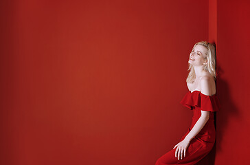 Image showing Beautiful young adult woman wearing red jumpsuit standing next t