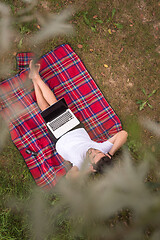 Image showing top view of man using a laptop computer under the tree