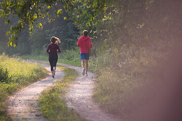 Image showing young couple jogging along a country road