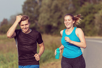 Image showing young couple jogging along a country road