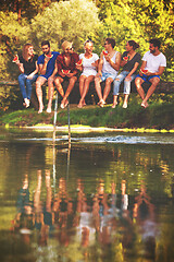 Image showing friends enjoying watermelon while sitting on the wooden bridge