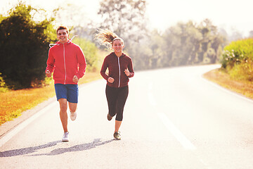 Image showing young couple jogging along a country road