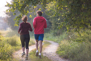 Image showing young couple jogging along a country road