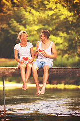 Image showing couple enjoying watermelon while sitting on the wooden bridge