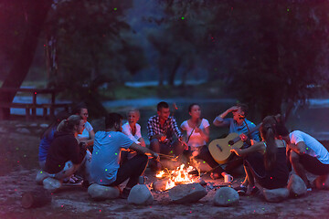 Image showing young friends relaxing around campfire