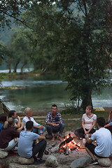 Image showing young friends relaxing around campfire