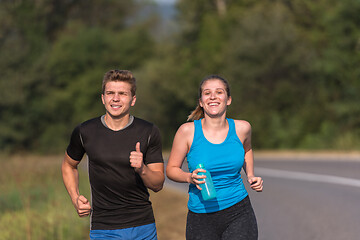 Image showing young couple jogging along a country road