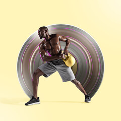 Image showing Young african-american bodybuilder training over yellow background