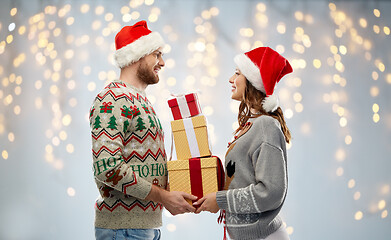 Image showing happy couple in christmas sweaters with gifts