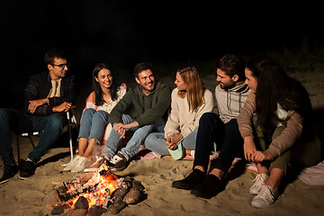 Image showing group of friends sitting at camp fire on beach