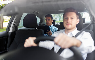 Image showing man with tablet pc and earphones riding in car