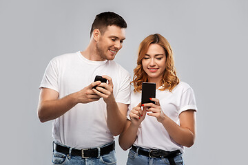 Image showing happy couple in white t-shirts with smartphones