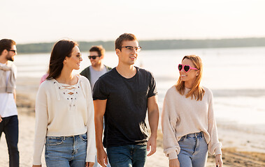 Image showing happy friends walking along summer beach