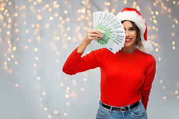 Image showing happy woman in santa hat with money on christmas