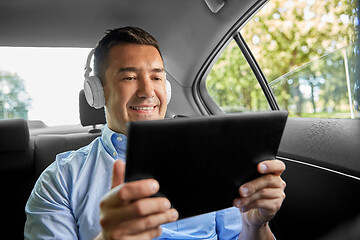 Image showing passenger with headphones using tablet pc in car