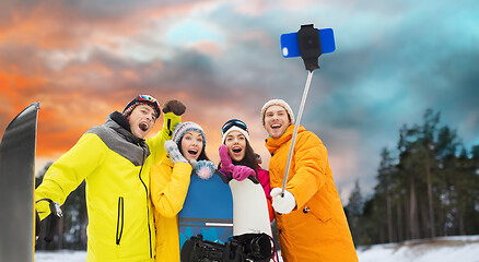 Image showing happy friends with snowboards and smartphone