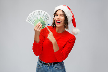 Image showing happy woman in santa hat with money on christmas