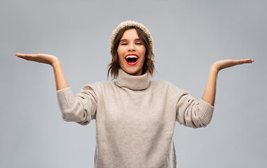 Image showing young woman in winter hat holding something