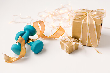 Image showing christmas gift boxes and dumbbells on white