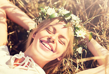 Image showing happy woman in wreath of flowers lying on straw