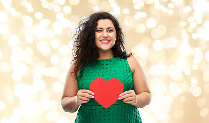 Image showing happy woman holding red heart over lights