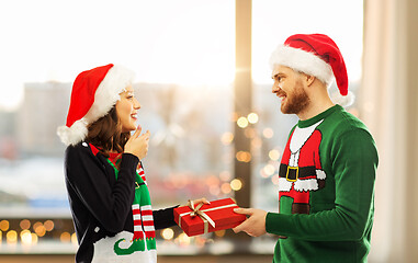Image showing happy couple in christmas sweaters with gift box