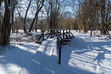 Image showing Snowy trail with wooden footbridge 